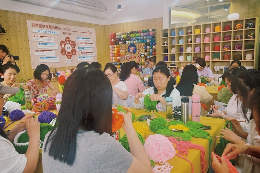 成都市武侯区华兴街道三河社区就业服务小站，居民们正在学习制作一款花朵包。人民网记者 郭莹摄