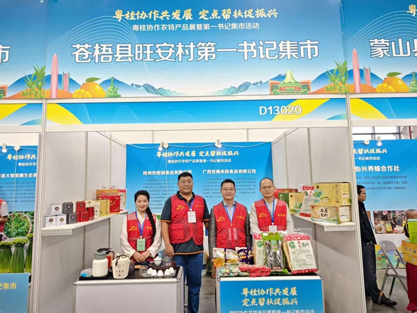 四位驻村工作队员在展位前合影